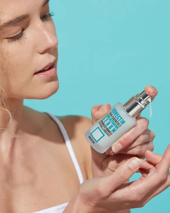 Woman holding a skincare bottle against a blue background