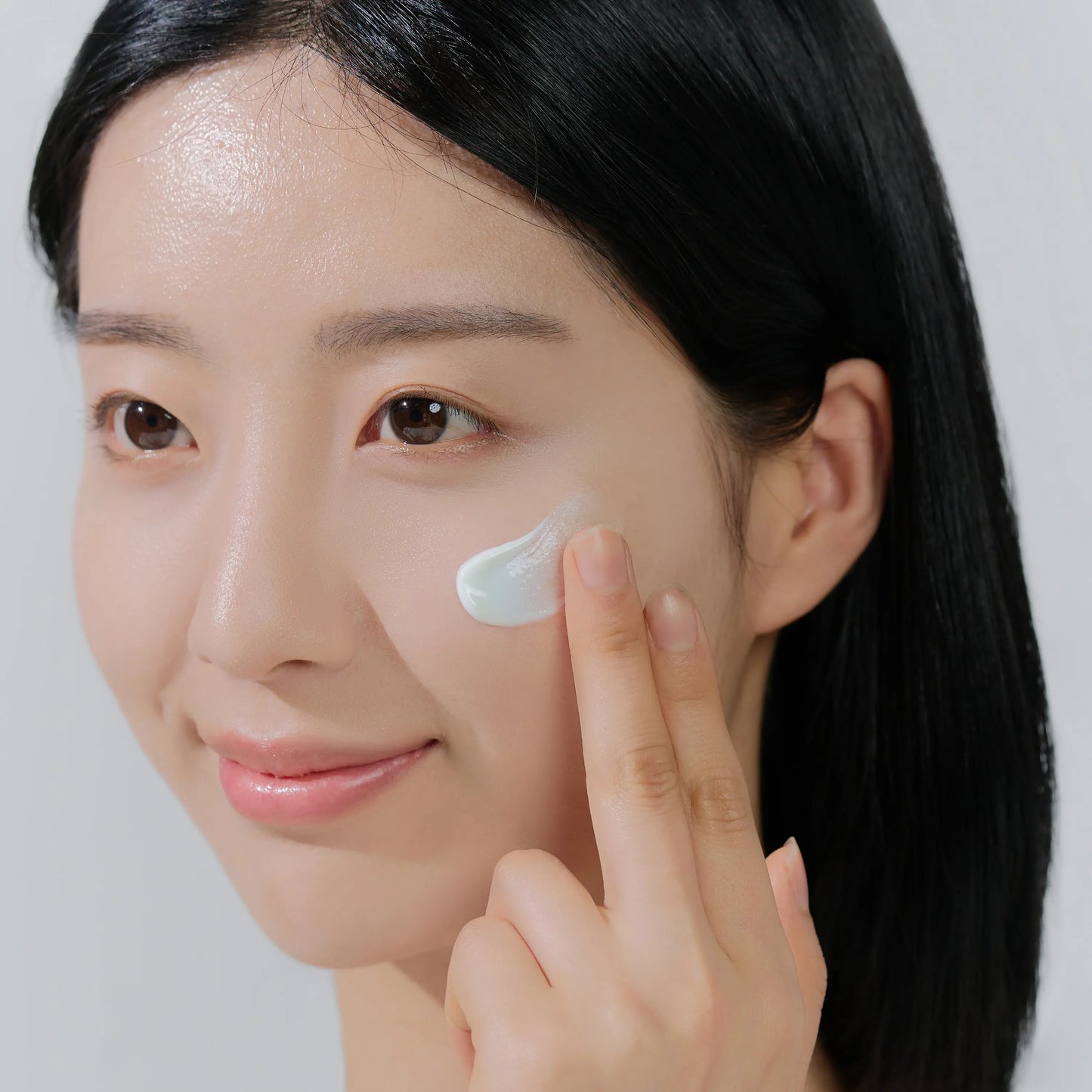 Applying SKIN1004 Hyalu-Cica Water-Fit Sun Serum evenly on face for broad spectrum SPF50 sun protection