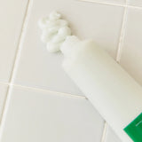 Aromatica Rosemary Scalp 3-in-1 Treatment squeezed tube laying on tile