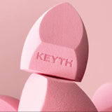 Pink makeup sponge with 'KEYTH' branding on a pink background