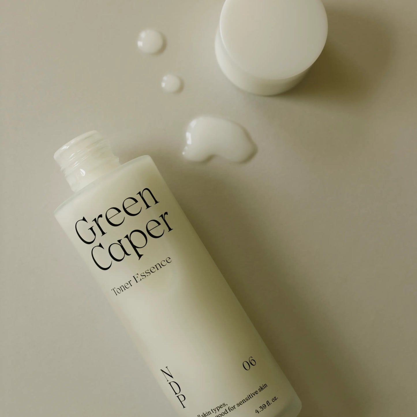 Close-up of NDP Green Caper Toner Essence highlighting clear watery formula and lightweight hydrating texture