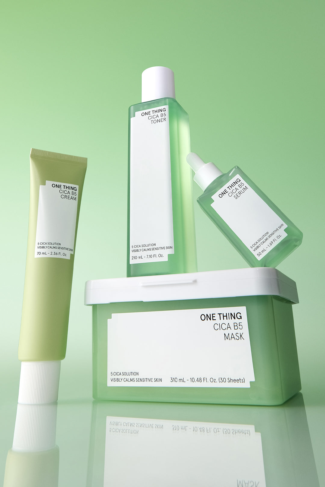 This image features a collection of skincare products, prominently displaying the ‘Cica B5 Serum’. The product is presented in a sleek, white bottle with a minimalist design, topped with a pump dispenser for easy application.