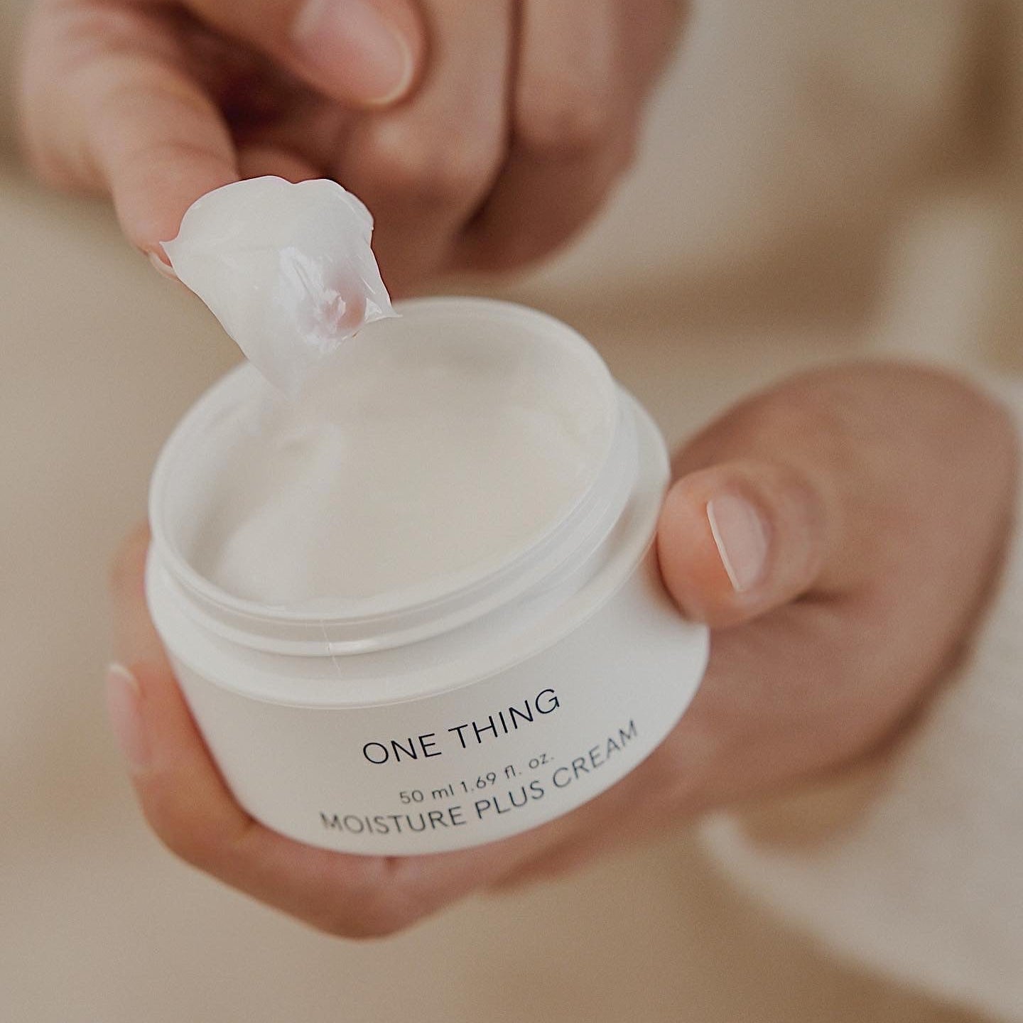 One Thing Moisture Plus Cream being scooped from jar by hand
