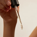 One Thing Tangerine Serum dropper held in hand with texture